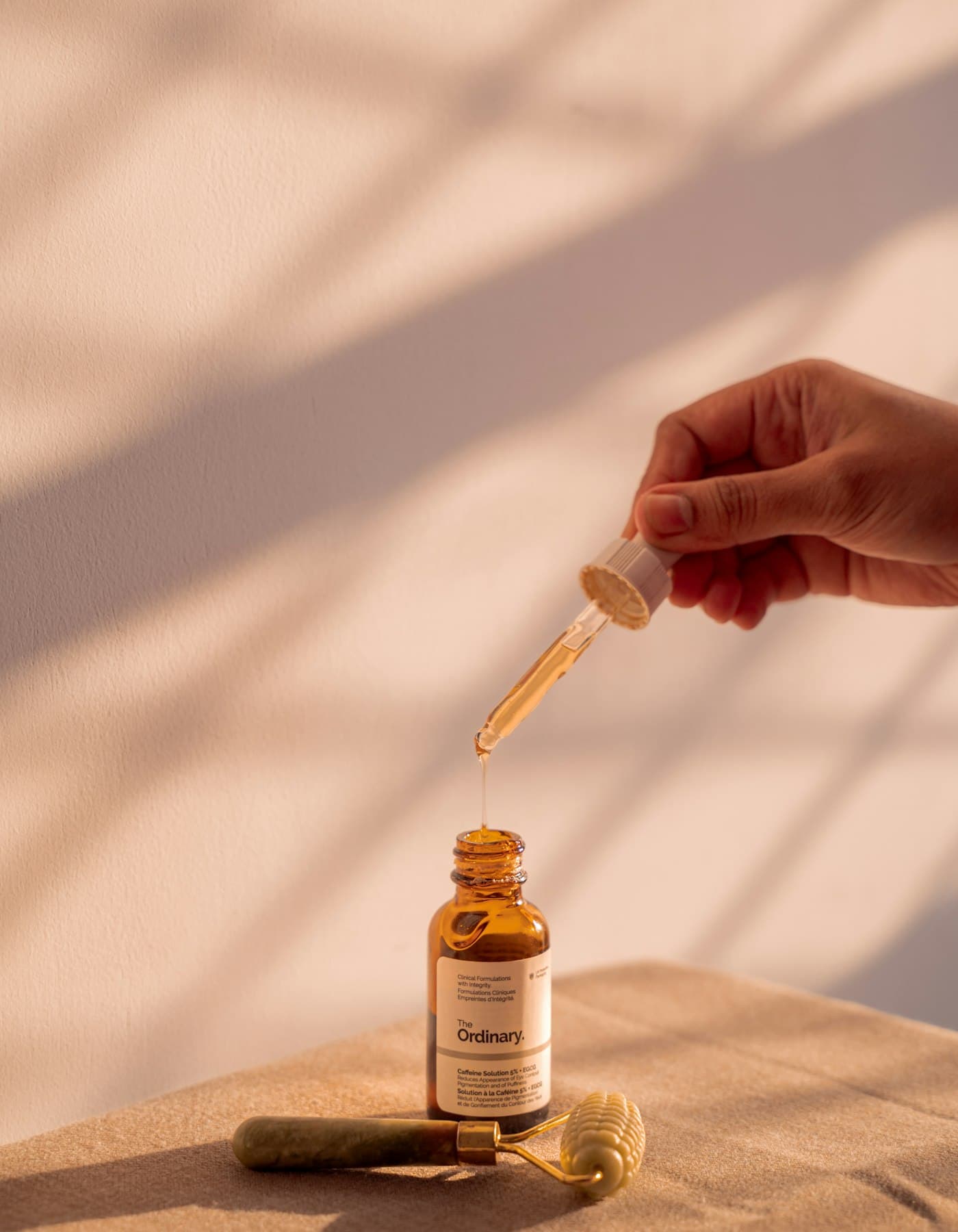 Conta-gotas pingando sérum em um frasco âmbar, sob luz natural